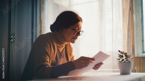 Senior woman reading a letter with bad news and crying, debts and poverty photo