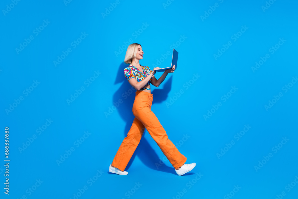 Full length profile portrait of nice person walk use laptop empty space isolated on blue color background