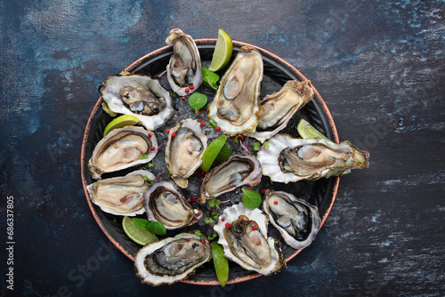 Fresh oysters with lime on round plate. Oyster in half shell. Flat lay. Top view. Copy space.