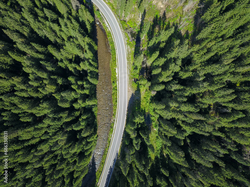 Aerial drone panorama above Sebes river flowing through a coniferous forest along an asphalt road. Carpathia, Romania.