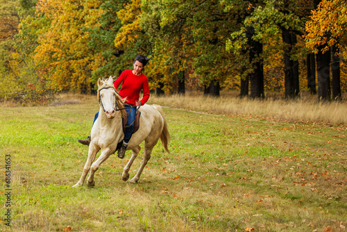 A pretty young woman and a white horse turning in the meadow