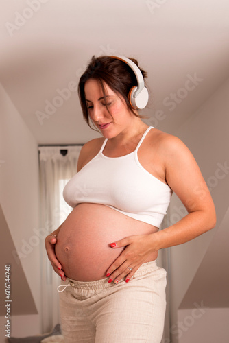 Beautiful pregnant woman, dancing and listening to music on the bed. High quality photo photo