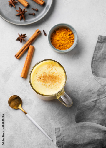 Turmeric golden milk latte with spices and honey. Detox, immunity boosting, anti-inflammatory, healthy, cozy drink in a glass cup on a light background