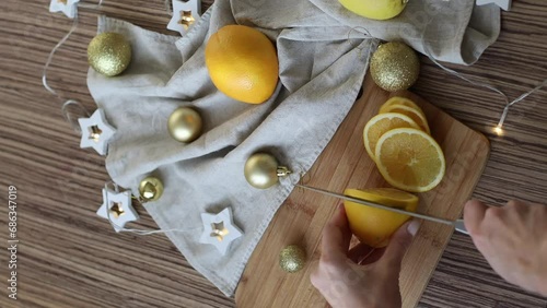New Year's layout of oranges, boards, napkins, garlands and balloons on the kitchen table.Preparations for the holiday.Preparing for the celebration of Christmas.The girl cuts oranges with a knife.