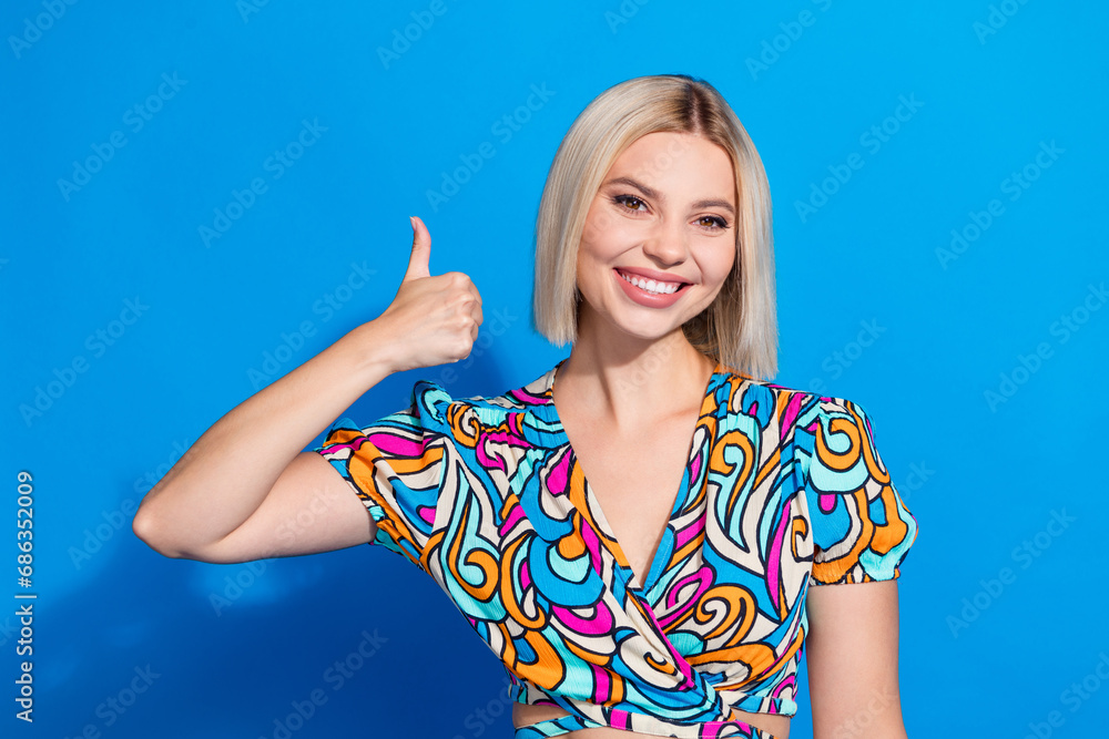 Portrait of cheerful pretty lady beaming smile arm finger demonstrate thumb up isolated on blue color background Portrait of cheerful pretty lady beaming smile arm finger demonstrate thumb up isolated on blue color background
