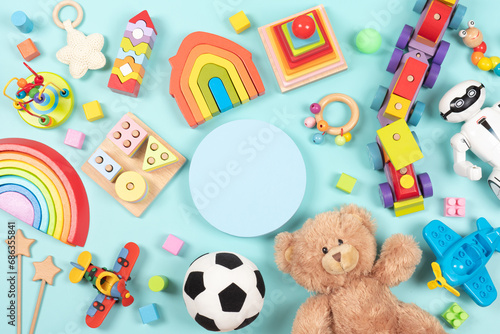 Empty round platform podium stand  with teddy bear  robot and many natural wooden ecological sustainable educational children toys. Baby kid toys on light blue background. Top view  flat lay