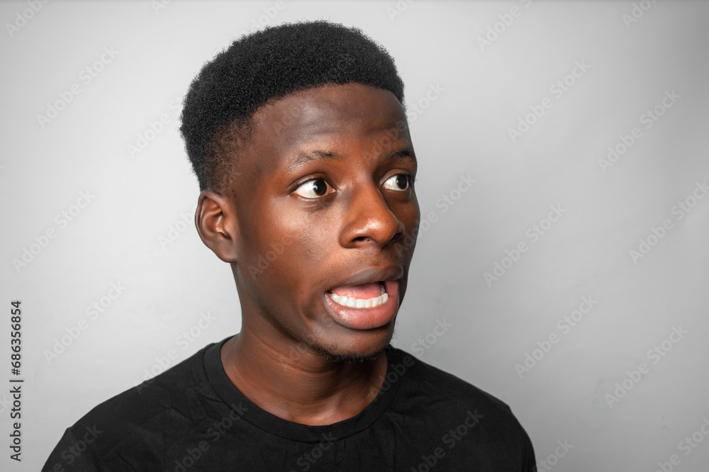 Fototapeta premium Happy cheerful young African gen Z isolated on white background. Funny confused state of mind and shock