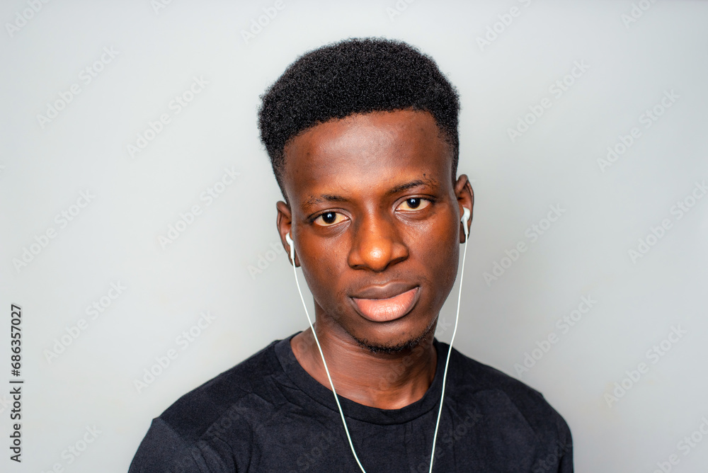 Happy cheerful young African gen Z isolated on white background. Funny confused state of mind plugs earpiece to ear with optimistic look - obrazy, fototapety, plakaty 