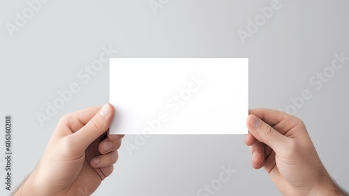 a man's hand holding a blank, simple white business card design mockup, the absence of text and the potential for business branding against a light background.