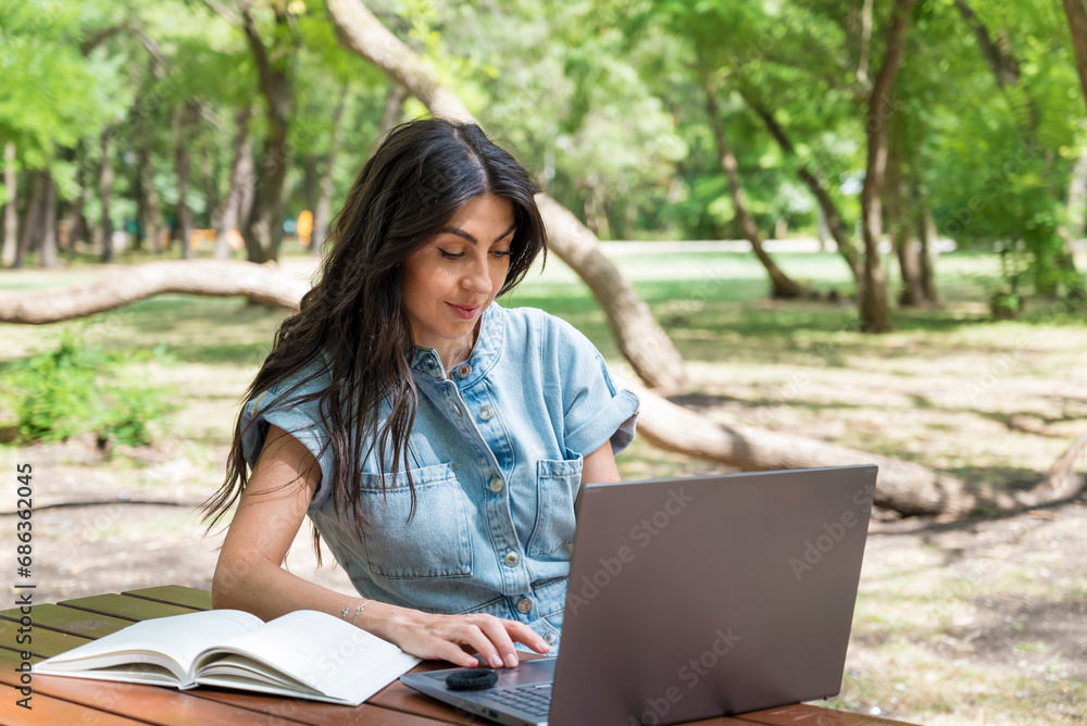 Portrait of pretty young woman sitting in the summer park using laptop Portrait of pretty young woman sitting in the summer park using laptop