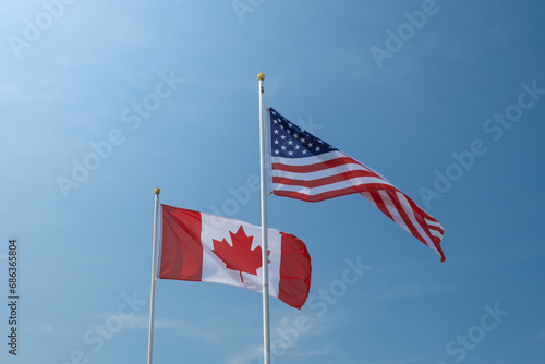 Quadro su tela USA and Canadian flags waving left to right against blue sky