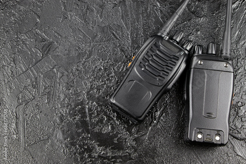 Pair of portable radio station on black graphite background, walkie-talkie. Security devices . Radio transmission on a stone background. Signal transmission, radio signal. Copy space.
