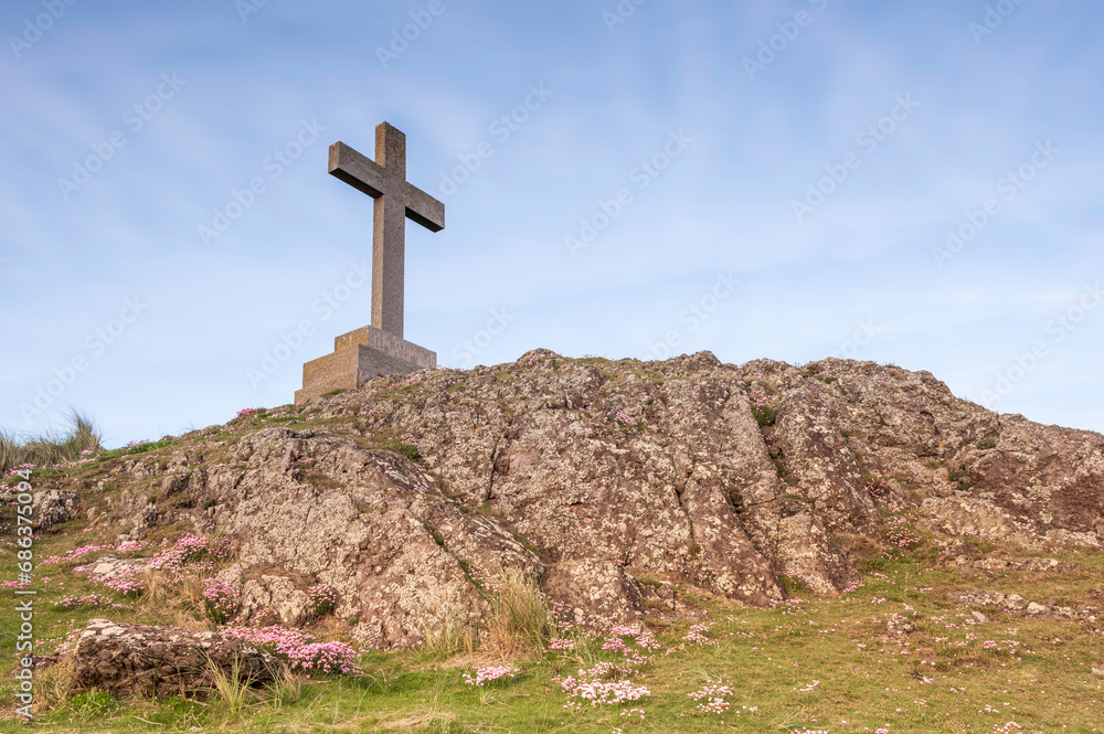 View of Christian Cross on Ynys Llanddwyn Island in Angelsey, against a blue sky View of Christian Cross on Ynys Llanddwyn Island in Angelsey, against a blue sky