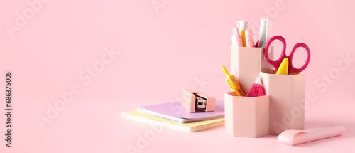 Holder with different stationery on pink background with space for text