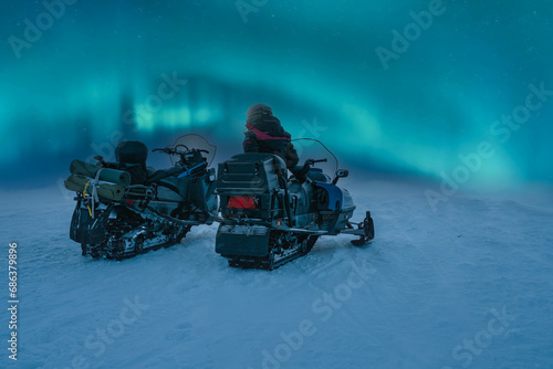 фотографія Scenic view at two snowmobiles stand close at snowy and windy mountain top