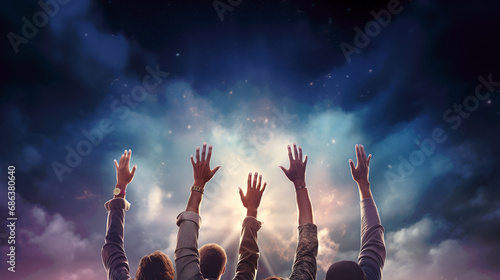 People raising their arm to the sky, to pray, cheer, great, or show solidarity. Group of happy people on dark sky background with sunlight and clouds, waving, cheering, and welcoming. Copy space.