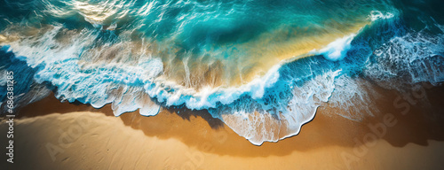 Aerial top down view ocean waves breaking on golden sand beach. Sea foam and turquoise water at sunset light. Panorama with copy space.