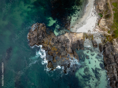 drone view of waves crashing against rocks in ocean