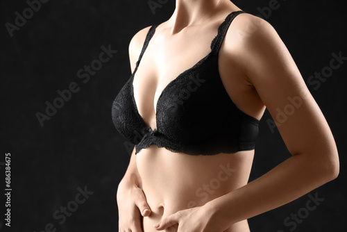 Young woman in bra on black background