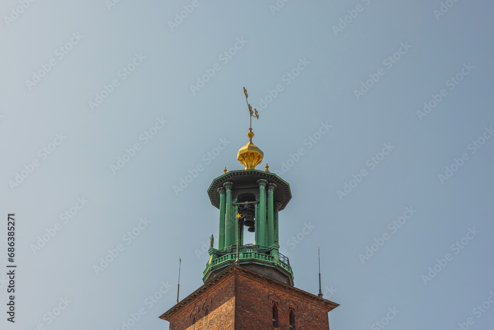 Detailed perspective of cathedral dome adorned with bells against backdrop of clear blue sky. Sweden.