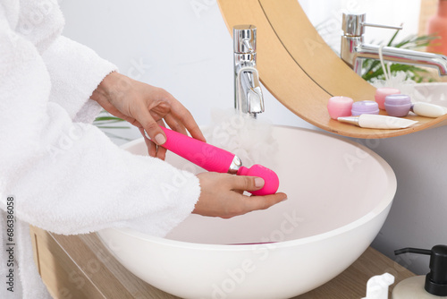 Fototapeta Naklejka Na Ścianę i Meble -  Woman washing vibrator over sink in bathroom, closeup