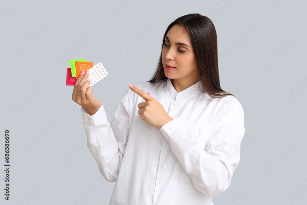 Female gynecologist pointing at contraceptives on light background Female gynecologist pointing at contraceptives on light background