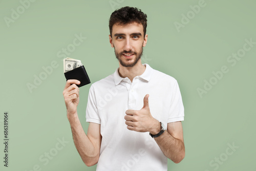 Young man with wallet showing thumb-up on green background