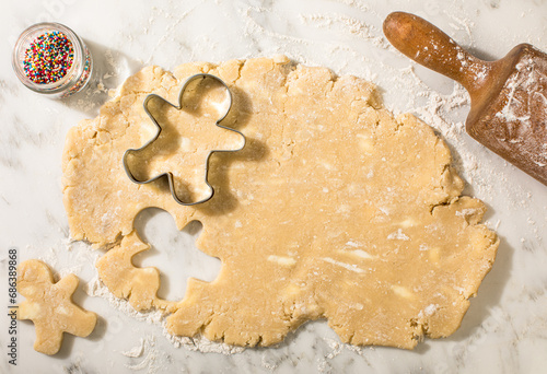 Sugar cookie dough with snowman cookie cutters and rolling pin
 photo