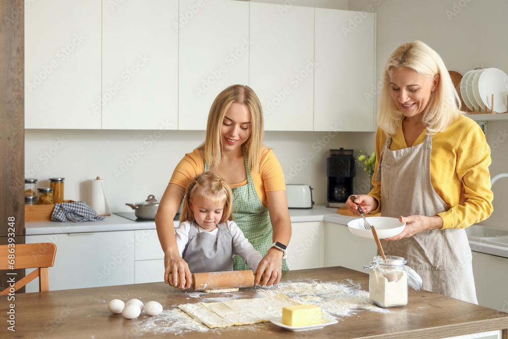 Cute little girl with her mother and granny preparing dough in kitchen Cute little girl with her mother and granny preparing dough in kitchen
