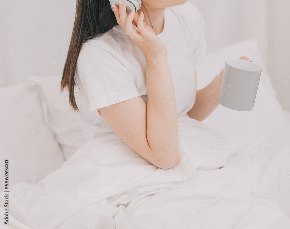 Efficient Young Millennial Girl Sitting on a Bed in the Morning, Uses Laptop Computer and Eats Croissants and Drinks Coffee for Breakfast Efficient Young Millennial Girl Sitting on a Bed in the Morning, Uses Laptop Computer and Eats Croissants and Drinks Coffee for Breakfast