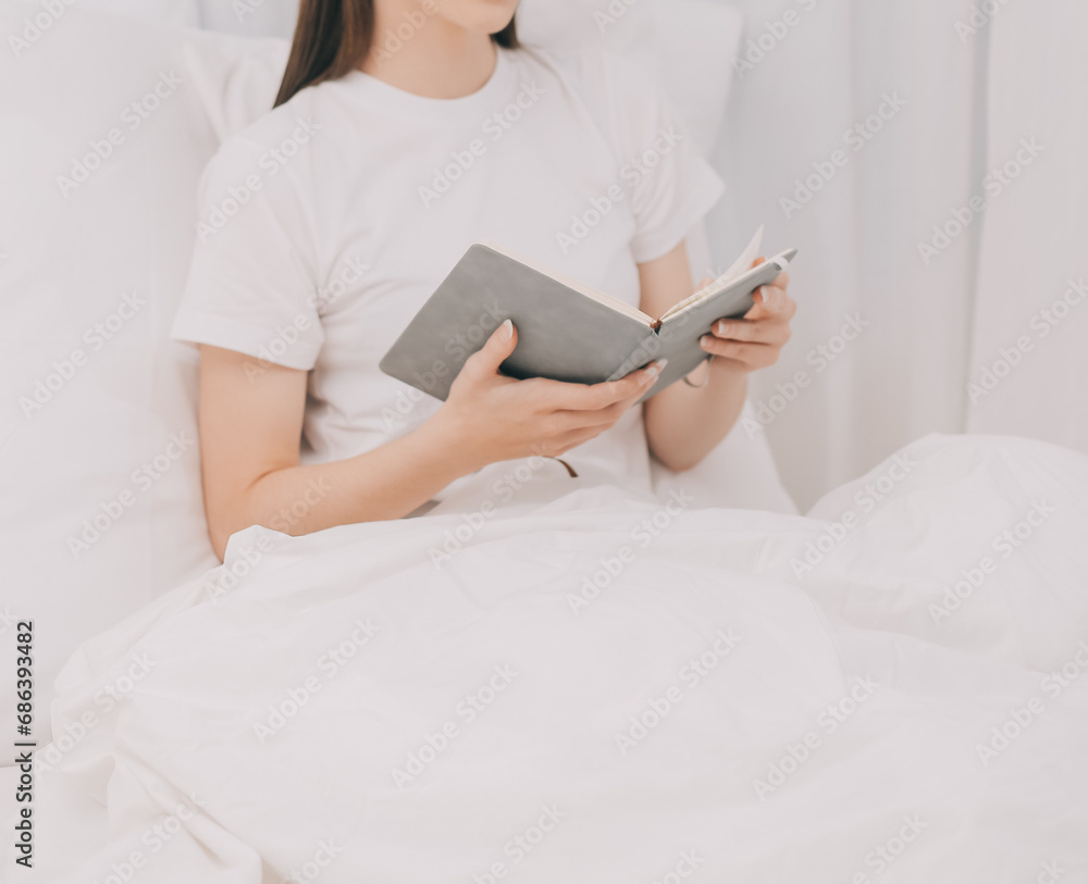 Efficient Young Millennial Girl Sitting on a Bed in the Morning, Uses Laptop Computer and Eats Croissants and Drinks Coffee for Breakfast Efficient Young Millennial Girl Sitting on a Bed in the Morning, Uses Laptop Computer and Eats Croissants and Drinks Coffee for Breakfast