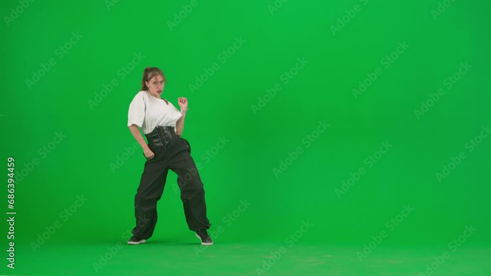 In the frame on a green background, chromakey. A young, slender, beautiful girl is dancing. She demonstrates various dance moves in the direction of jazz funk. She is rhythmic, plastic. General plan
