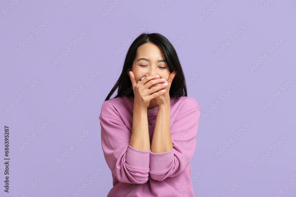 Young Asian woman laughing on lilac background Young Asian woman laughing on lilac background