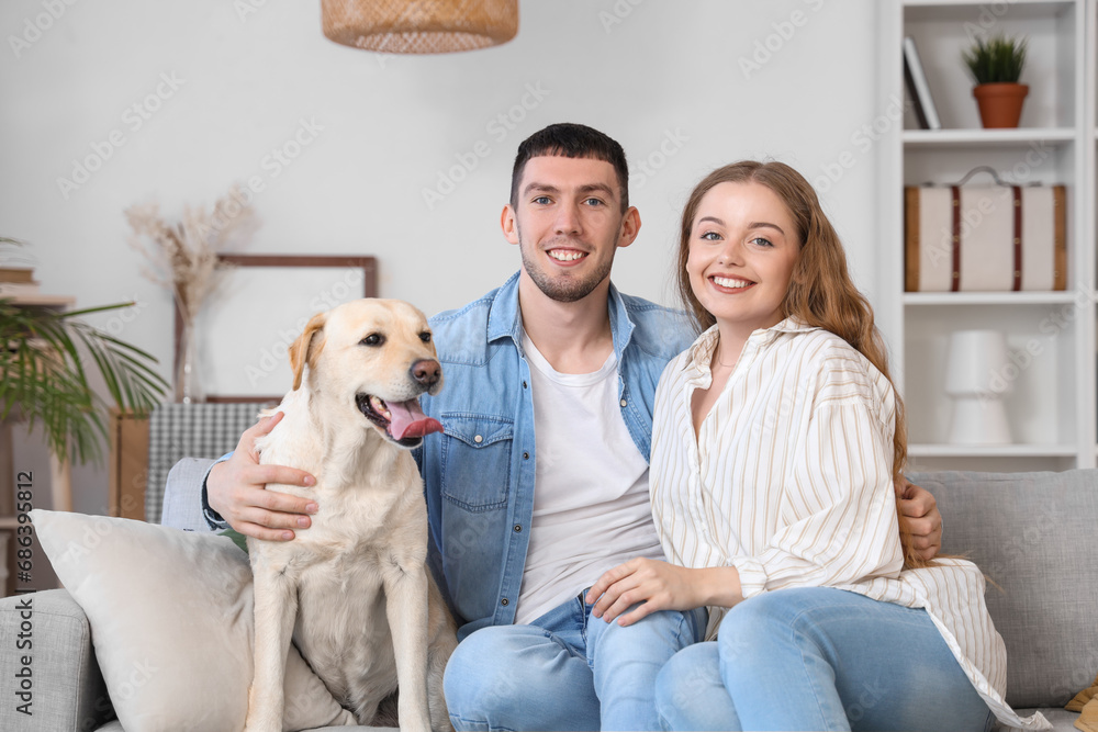 Happy young couple with Labrador dog sitting on sofa at home Happy young couple with Labrador dog sitting on sofa at home