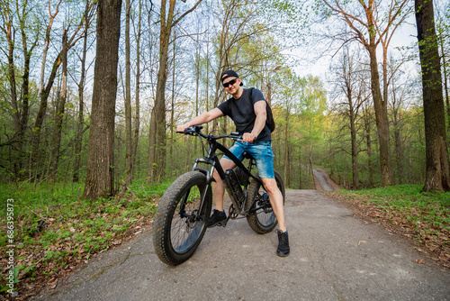 Man on a fatbike in the woods. Pleasant sports hobby. Concept of a healthy lifestyle.