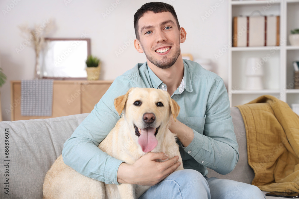 Young man with Labrador dog sitting on sofa at home Young man with Labrador dog sitting on sofa at home