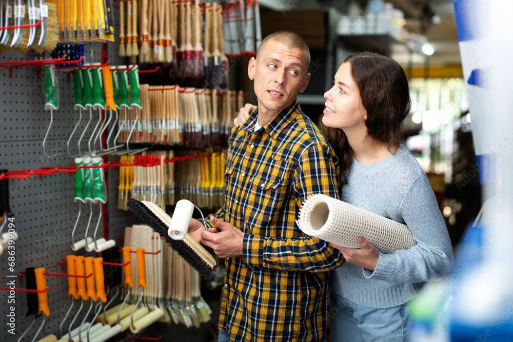 Positive couple choosing supplies for home renovation in shop of building materials