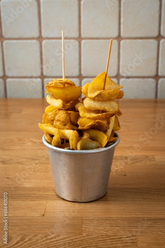 bucket with unpeeled french fries on wooden table