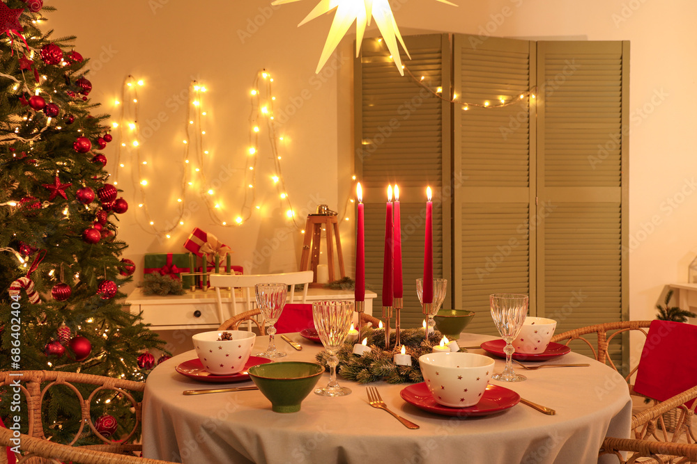 Interior of festive room with Christmas tree, decorations and served dining table at evening