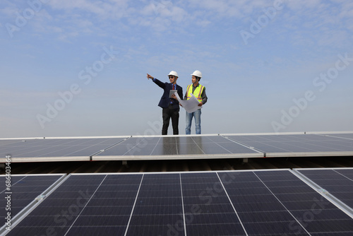 Solar Energy project management and Engineer energy power work as a blueprint equipment construction and laptop at photovoltaic panels on solar roofs with the concept of renewable and Sustainable ener