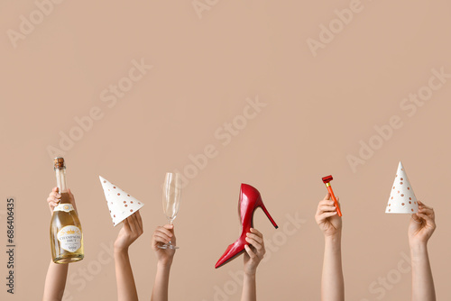 Female hands with birthday party items, bottle of champagne and stylish high heel shoe on color background