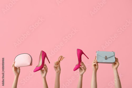 Female hands with stylish shoes and accessories on pink background