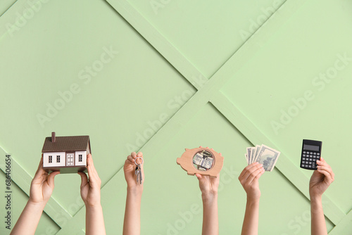Female hands with house figure, keys, money and calculator against color wall. Concept of buying real estate