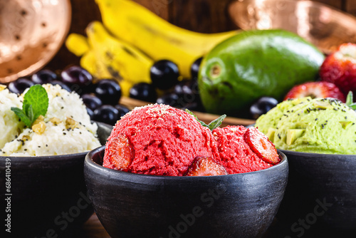 vegan ice cream made with organic fruits, with tropical fruits in the background, flavors of strawberry, banana, jabuticaba and avocado photo