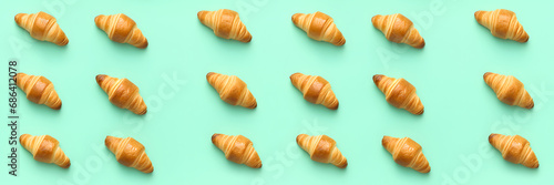 Seamless pattern with croissants on pastel green background. Photo of croissants in flat lay aerial view. Background with croissants for print, advertisement, graphic design,