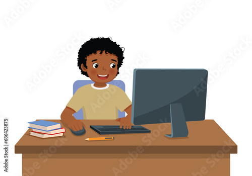 Cute little African boy student study using Computer PC at the desk