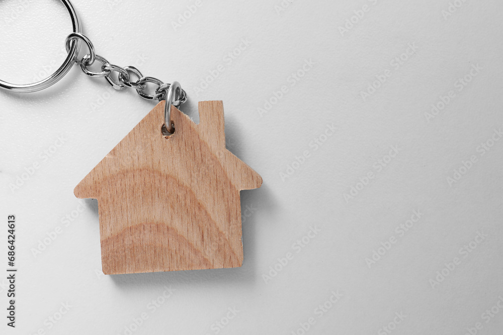 Wooden keychain in shape of house on light table, top view. Space for text Wooden keychain in shape of house on light table, top view. Space for text