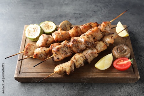 Delicious shish kebabs with vegetables and lemon on grey table