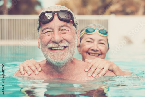 two seniors at the pool hugged together and playing - happy mature people and couple of pensioners looking at the camera smiling photo