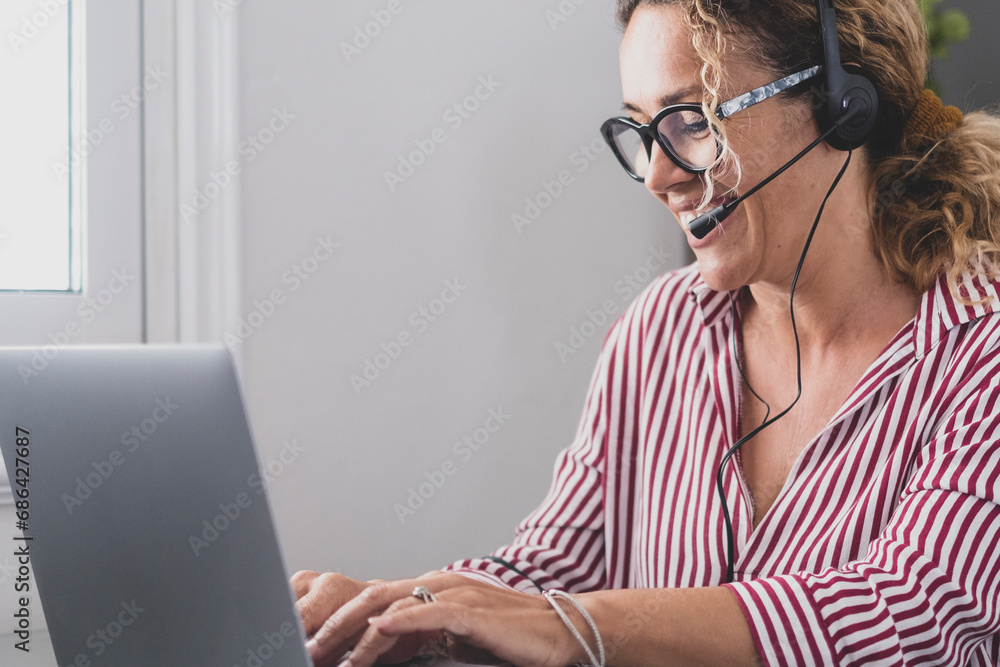 Attractive caucasian woman sit at home office room wearing headset take part in educational webinar using laptop. Video call event with clients or personal chat with friend remotely concept. Attractive caucasian woman sit at home office room wearing headset take part in educational webinar using laptop. Video call event with clients or personal chat with friend remotely concept.